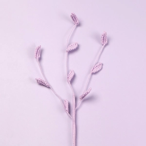 Macro shot of handmade crochet purple flower stems with detailed knitted leaf textures