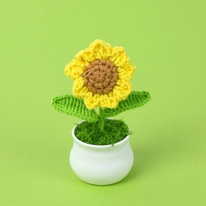 Handmade crochet sunflower in a white ceramic pot with vibrant yellow petals and green leaves