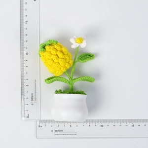 Detailed size view of a handmade crochet pineapple plant ornament in a white ceramic pot