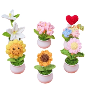 Fünf verschiedene handgehäkelte Blumen im Topf mit Sonnenblumen und Lilien als Dekoration