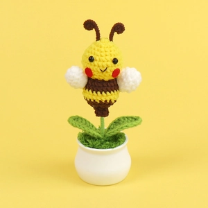 Close-up of handmade crochet honey bee plant in a white pot on yellow background