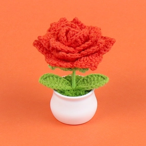 Close-up of handmade crochet red rose in white ceramic pot for home and desk decor