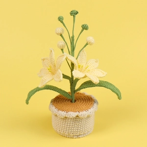 Macro shot of handmade crochet potted lilies with detailed yellow petals and green leaves