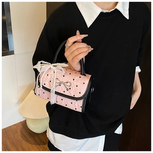 Detail of pink bow handbag with black heart patterns and silver butterfly buckle