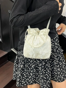 Elegant off-white bucket bag with butterfly embroidery shown as a stylish crossbody bag