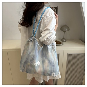 Detail of blue tie-dye tote bag with white floral embroidery and woven rope handle