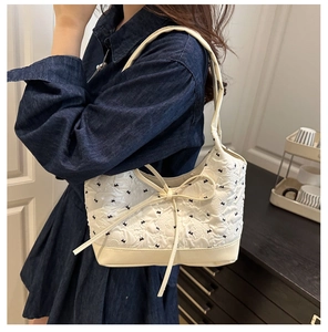 Detalle del bolso crema con tejido texturizado y bordado elegante de lazo negro