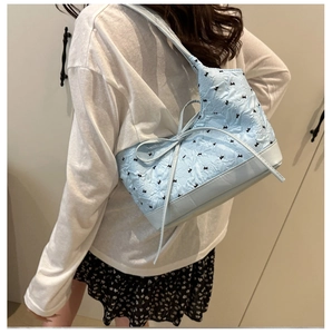 Détail du sac hobo bleu clair avec motifs mini nœuds et ruban porté par un mannequin