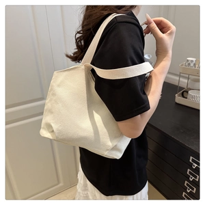 Detail of off-white canvas tote bag showing thick fabric texture and wide shoulder strap