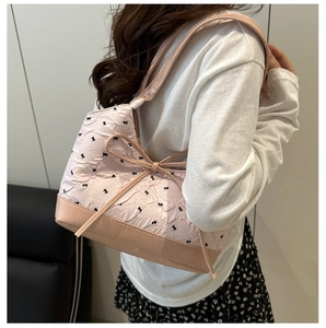 Detalle del bolso de hombro rosa con lazo, tela texturizada y cinta en la modelo