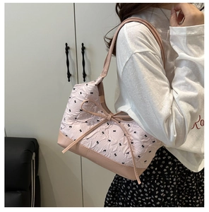 Vista detallada del bolso rosa con lazos, tejido de textura rugosa y correa de hombro de cuero