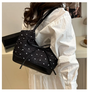 Detalle del bolso de hombro acolchado negro con bordado de lazos y base de cuero