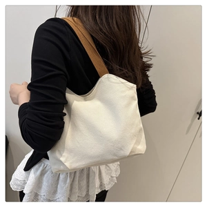 Back view of model carrying a minimalist canvas tote bag with brown straps