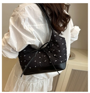 Detalle de bolso shopper negro con lazo grande y estampado de pequeños lazos blancos