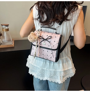 Dettaglio della borsa rosa con fiocco e ciondolo a orsetto indossata da una modella