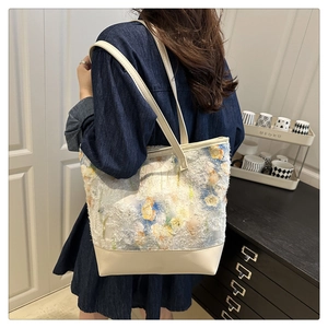 Dettaglio della borsa tote ricamata con motivi floreali blu e frange a nappa