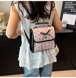 Dettaglio della borsa rosa in seersucker con ricami a fiocco nero e ciondolo a cuore