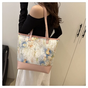 Dettaglio ravvicinato del ricamo floreale su borsa tote in tela con pelle rosa