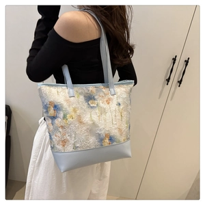 Dettaglio della borsa shopper bianca con ricami floreali e manici in pelle azzurra