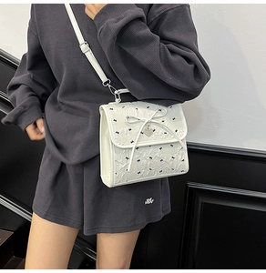 Dettaglio della borsa bianca in seersucker con ricami a fiocco nero e ciondolo a cuore