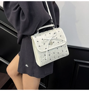 Dettaglio borsa bianca in seersucker con fiocchi neri e ciondolo a cuore