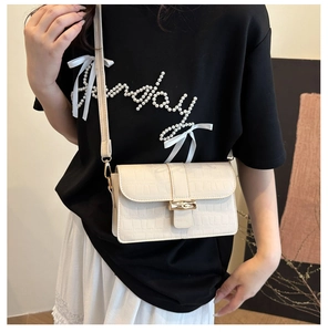 Detail of cream crocodile embossed leather handbag featuring a vintage bamboo twist lock