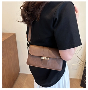 Detailed close-up of brown crocodile pattern shoulder bag with a gold bamboo clasp hardware