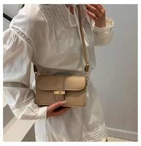 Detail of beige faux crocodile leather bag featuring a gold bamboo twist-lock closure