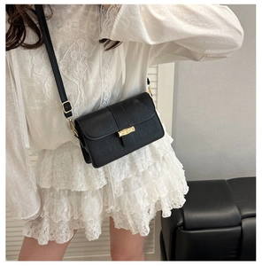 Detail of black waffle embossed leather bag featuring a signature gold bamboo clasp