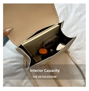 Internal capacity detail of beige shoulder bag showing storage for laptop and cosmetics