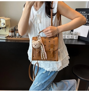 Detailed view of brown cartoon bear print backpack with stylish scarf and plush charm