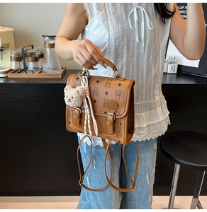 Detailed close-up of brown matte leather bag with bear patterns and plush charm