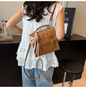 Detail of brown cartoon bear crossbody bag with plush charm and silk scarf decoration