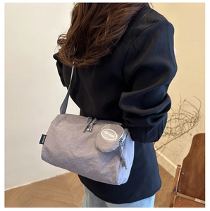Detailweergave van de grijze nylon cilindertas met een kleine ronde afneembare portemonnee