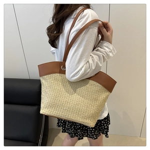 Detail of a large woven tote bag with brown faux leather trim and slender shoulder straps