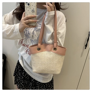 Detail of hand-woven beige raffia straw bag with pink faux leather straps and metal rings
