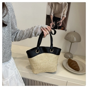 Detail of a French vintage straw tote bag with black splicing and gold ring accents