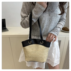 Detail of straw and black leather patchwork bag with gold eyelets and woven texture