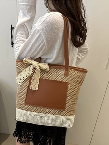 Large straw tote bag with brown leather pocket and cream lace bow for summer styling