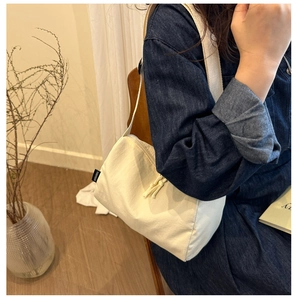 Gros plan sur un sac bandoulière en nylon blanc avec étiquette de marque minimaliste