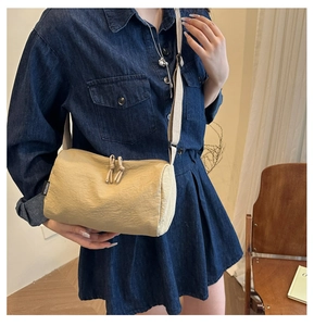 Close-up of beige nylon crossbody bag with dual zippers and wide strap on model