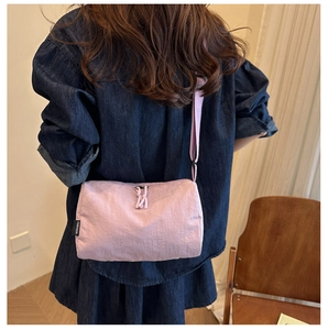 Détail de sac à bandoulière en nylon rose avec étiquette de marque et sangle réglable