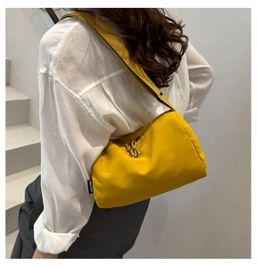Detail of yellow nylon crossbody bag featuring stylish knot zippers and cylinder shape