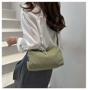 Close-up of light green nylon shoulder bag with fabric label and knotted zipper pull