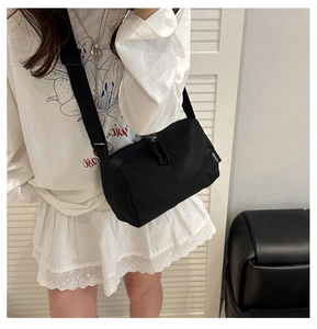 Détail du sac bandoulière cylindrique en nylon noir avec sangle large et étiquette