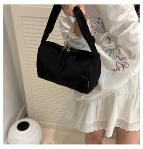 Détail d'un sac tonneau en nylon noir avec double fermeture éclair et étiquette tissée