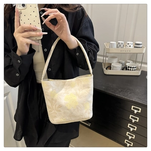 Detailaufnahme der cremefarbenen Stofftasche mit bestickten gelben Blumenmustern