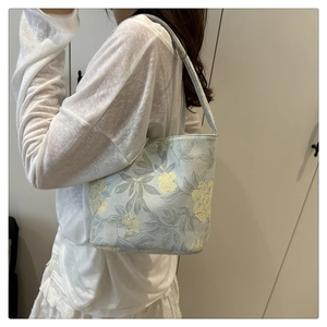 Detailansicht der Schultertasche mit Blumenmuster im Vintage-Stil an einem Model