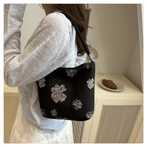 Detail einer schwarzen Segeltuch-Beuteltasche mit weißen floralen Mustern am Riemen