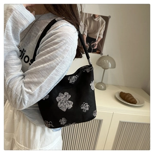 Detailansicht der schwarzen Retro-Beuteltasche mit weißen Blumenprints und Schultergurt
